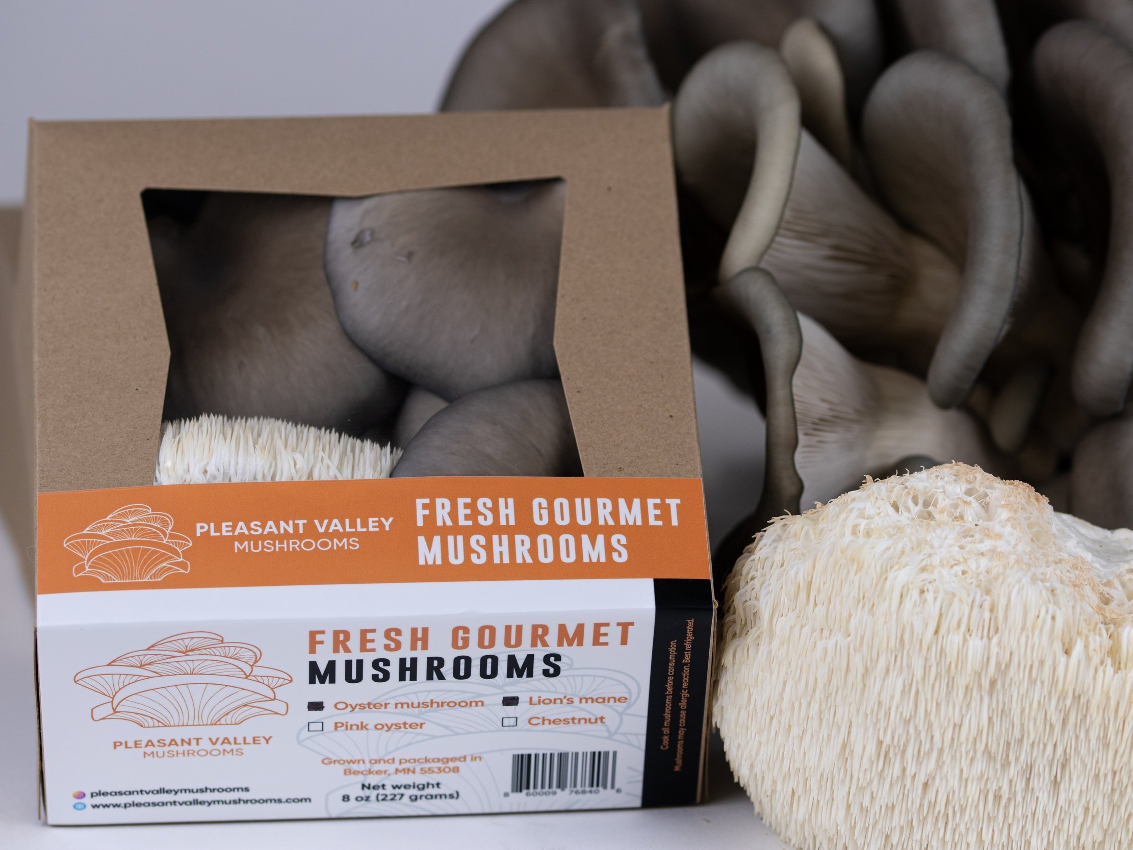 Fresh gourmet mushrooms from Pleasant Valley, featuring a variety of oyster mushrooms, including pink oyster, lion's mane, and chestnut. The packaging highlights the brand and includes details about the product's weight and origin from Becker, MN.